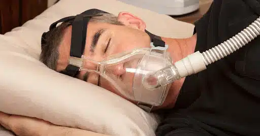 Man sleeping with a CPAP machine used to treat obstructive sleep apnea