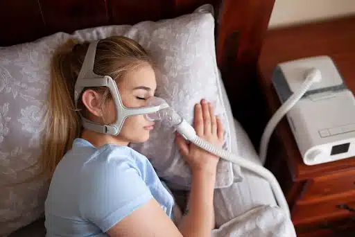Person sleeping with a CPAP device for nighttime sleep apnea treatment